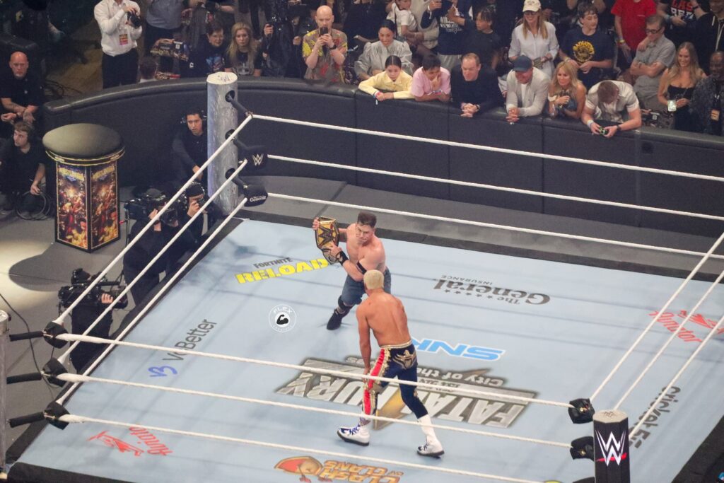 John Cena hits Cody Rhodes with the Undisputed Championship Belt after Travis Scott interrupted the match. 